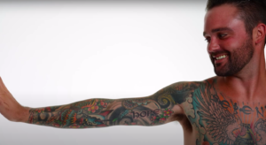 A perosn stands with their arm filled with tattoos out.