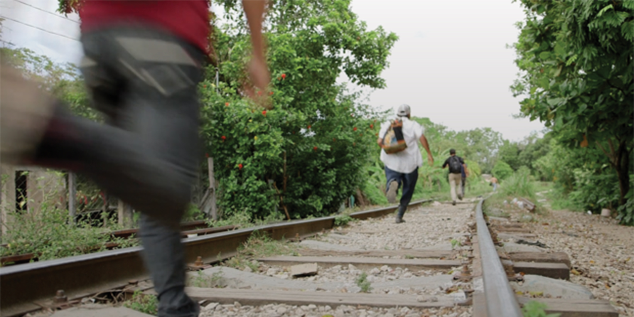 People flee across railroad tracks.