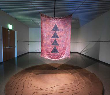 A reddish fabric with symbols hangs over a round mud-like object.