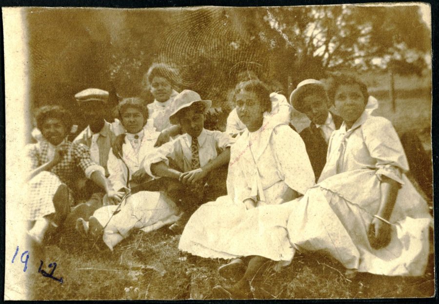Nine young African American men and women sitting in a field, Tulare County.