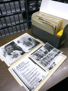 Black and white photos sit on top of a mail folder on a desk in a room with catalogue photos.