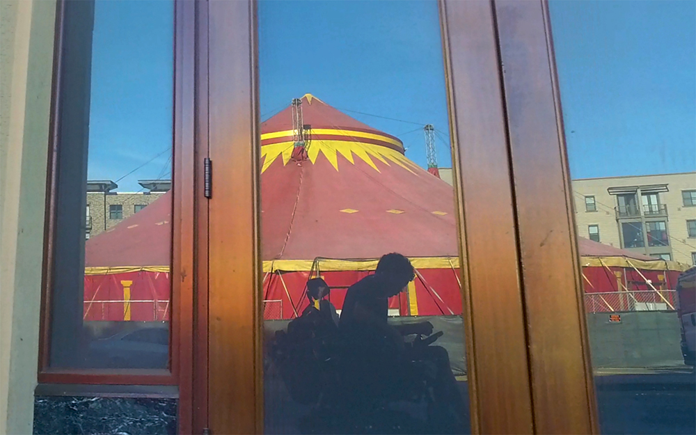 A person’s silhouette in front of a large red and yellow tent.