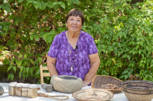 Ruth Orta stands behind a table covered with baskets.