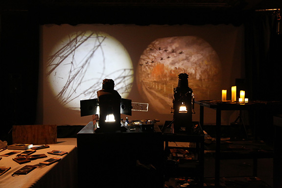 A dark room with two magic lanterns showing light projections on the wall.