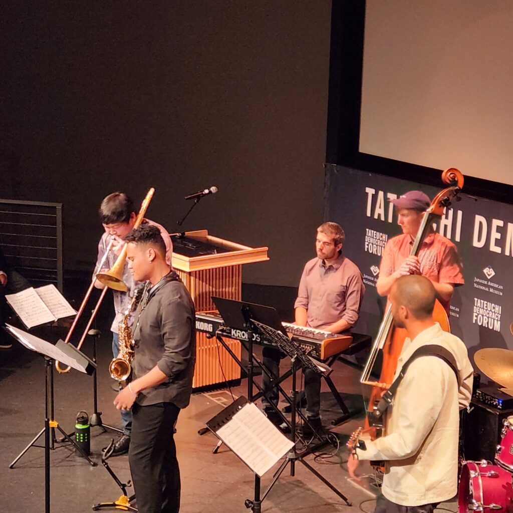 A jazz sextet performs. Includes trombone, sax, bass, piano, drums, and guitar