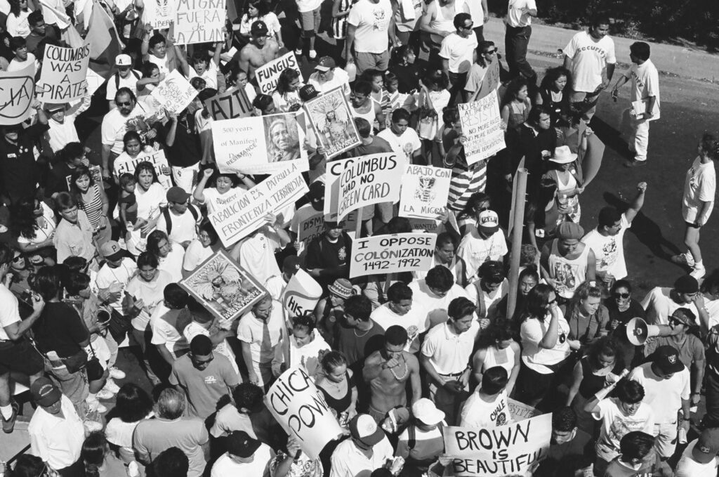 Black and white photo of protesters holding signs, seen from an aerial pov