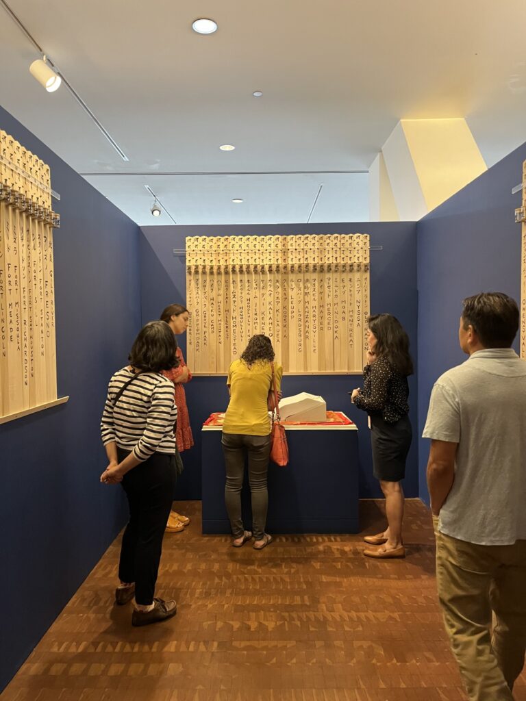 A group of people look at a large open book within an exhibit area.