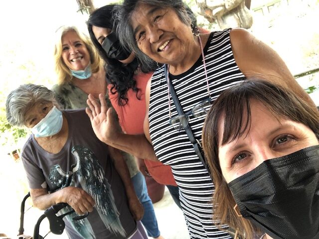 selfie with five people, four wearing masks.