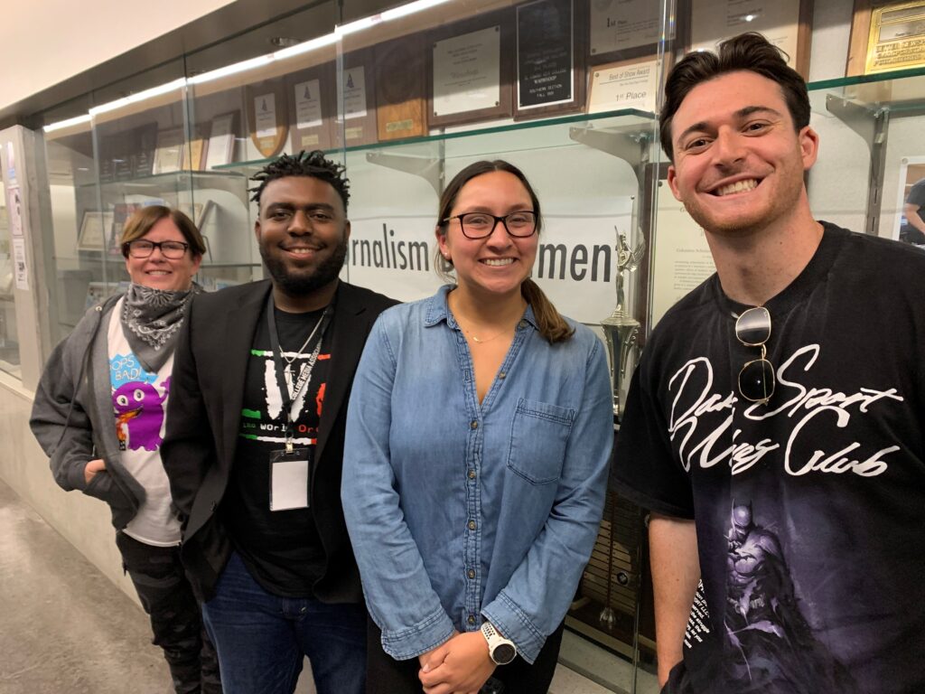 Four people smile and pose for the camera