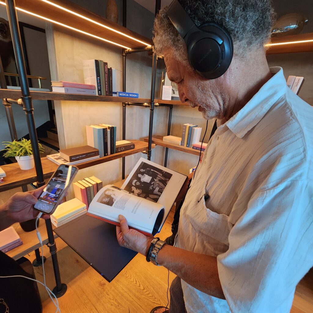 Man wearing black over-ear headphones flips through a picture book.