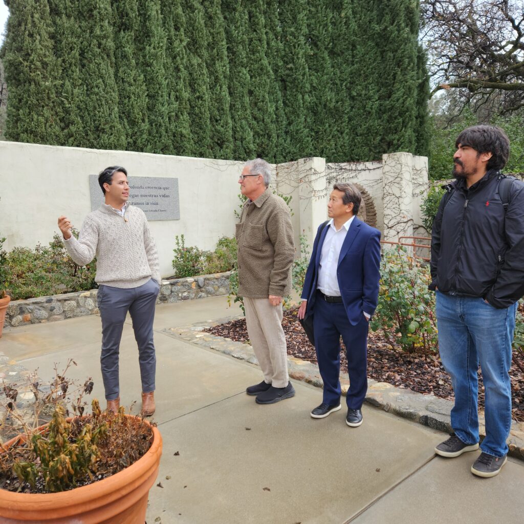 Four men stand outside in a memorial garden