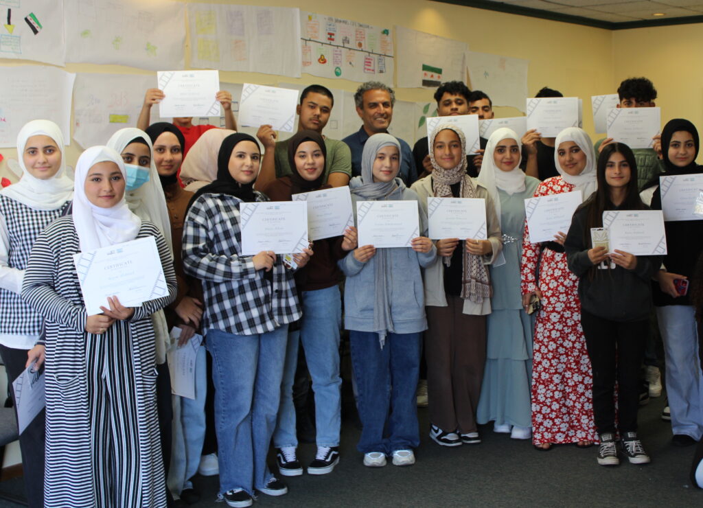 Group of youth pose for a photo holding up writing on pieces of paper