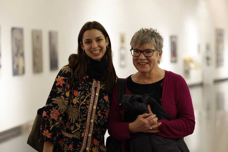 Two women pose for a photo inside a museum gallery space