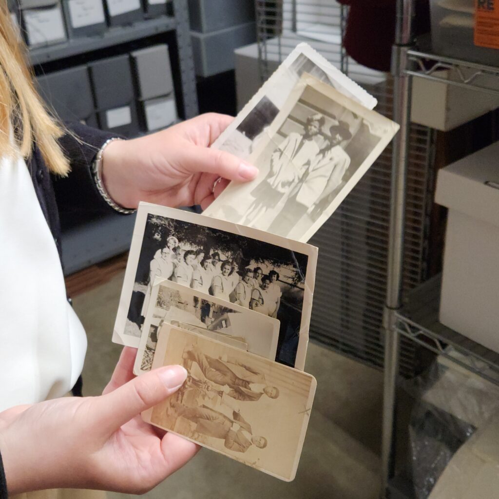 Close-up of hands holding a series of small historic photographs.