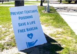 Photo of a sign on the grass reading Prevent Fentanyl poisoning save a life free narcan