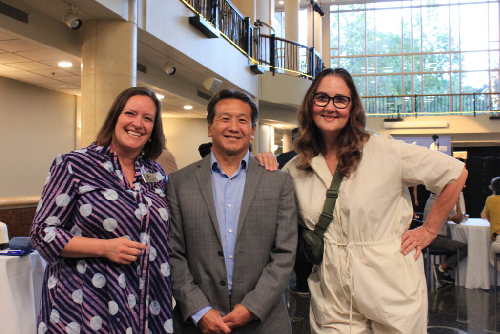 Three people pose for a photo inside a cavernous library atrium.