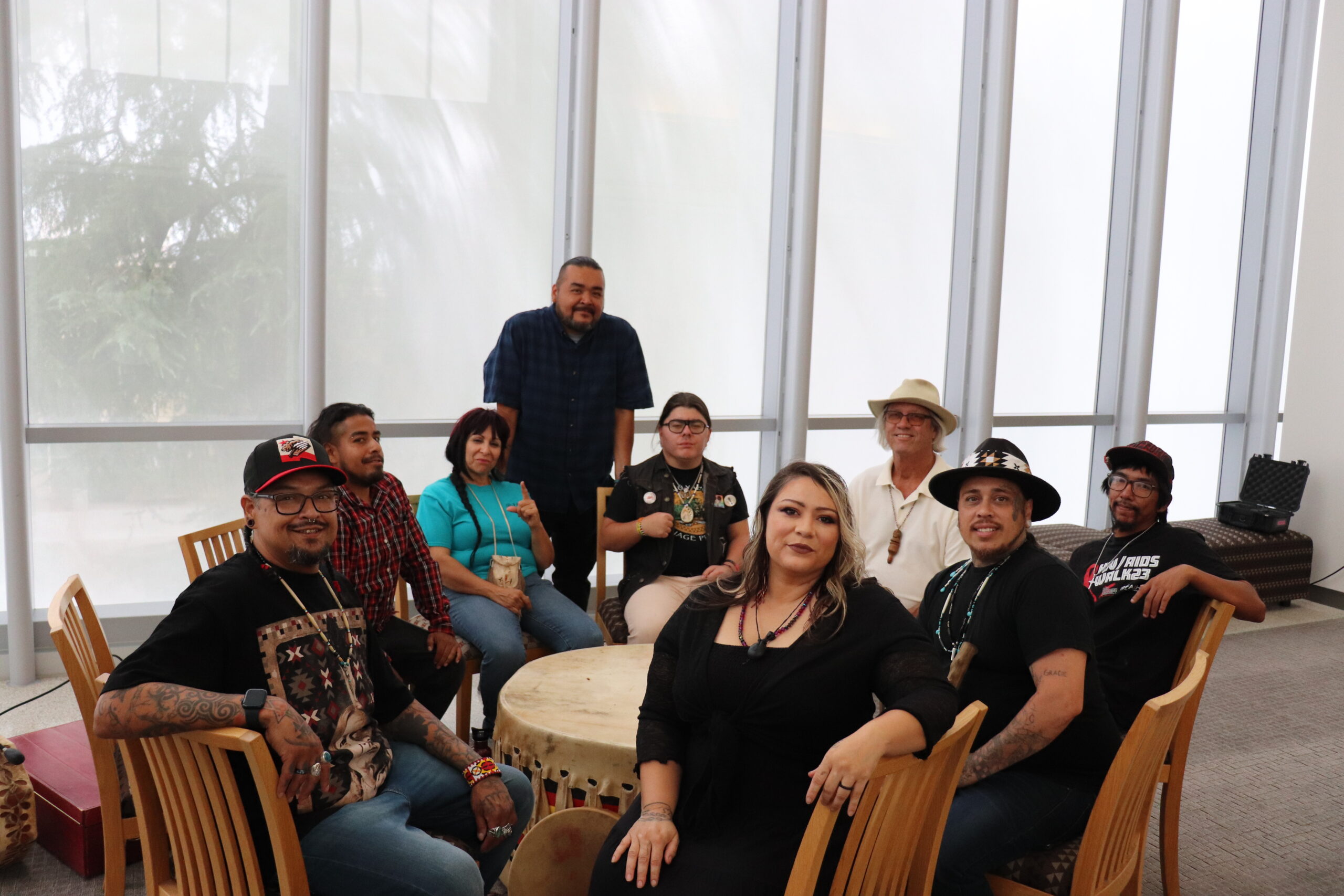 A group of people sit around a table and pose for a photo.